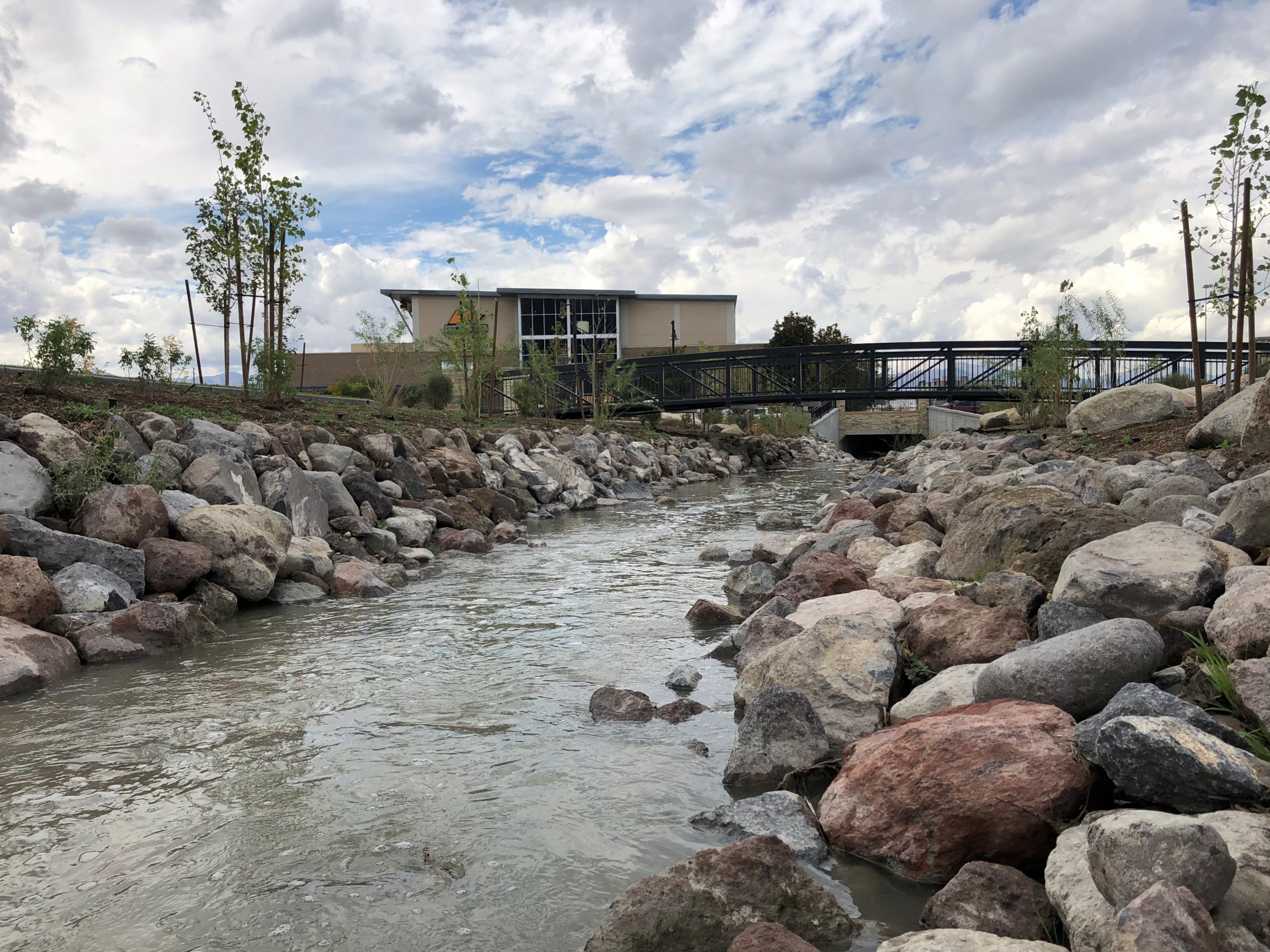Section of the Dry Creek channel with pedestrian bridge and building in the background.