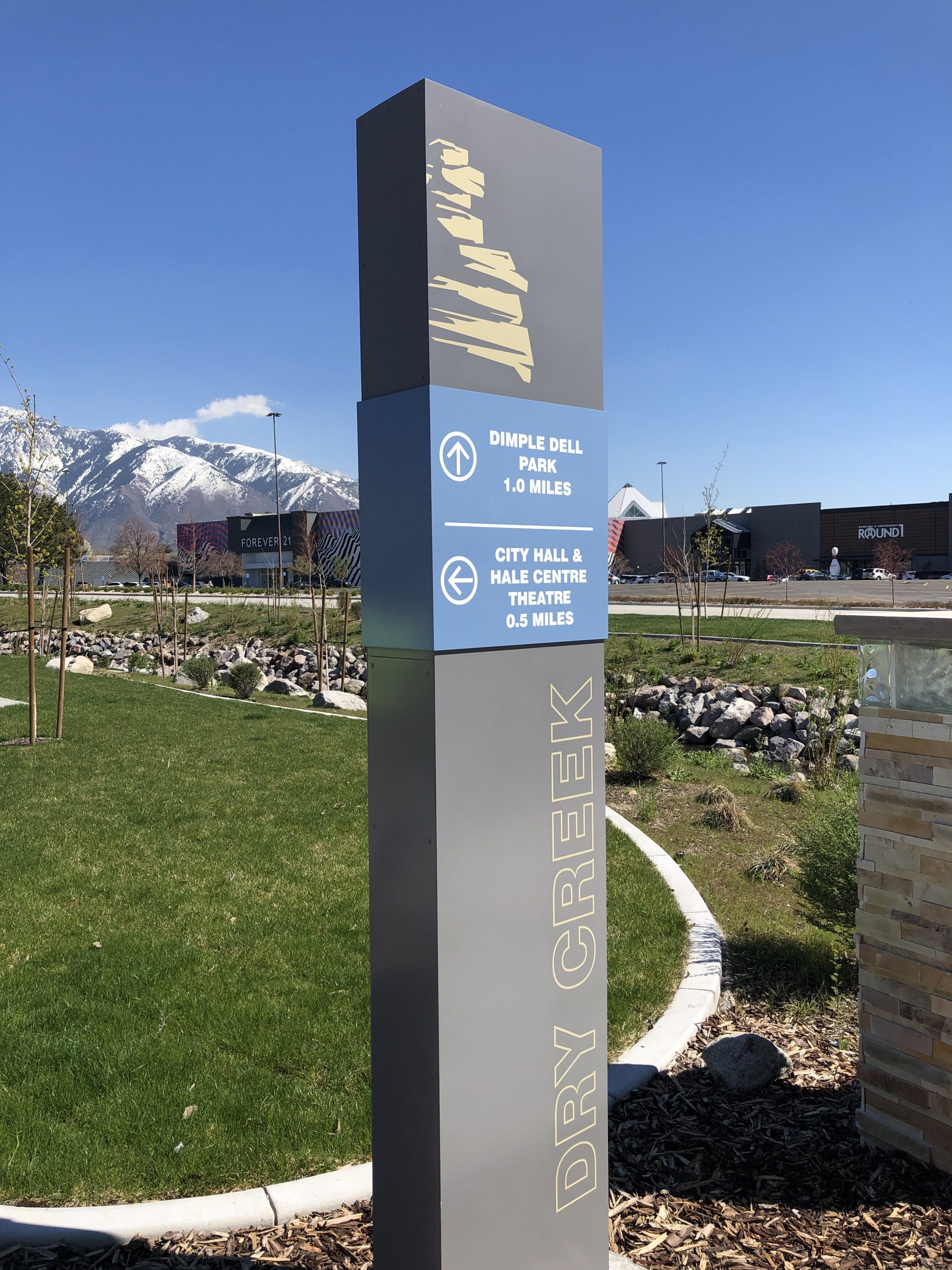 Sign marking Dry Creek channel with directions to nearby park, city hall, and theatre.