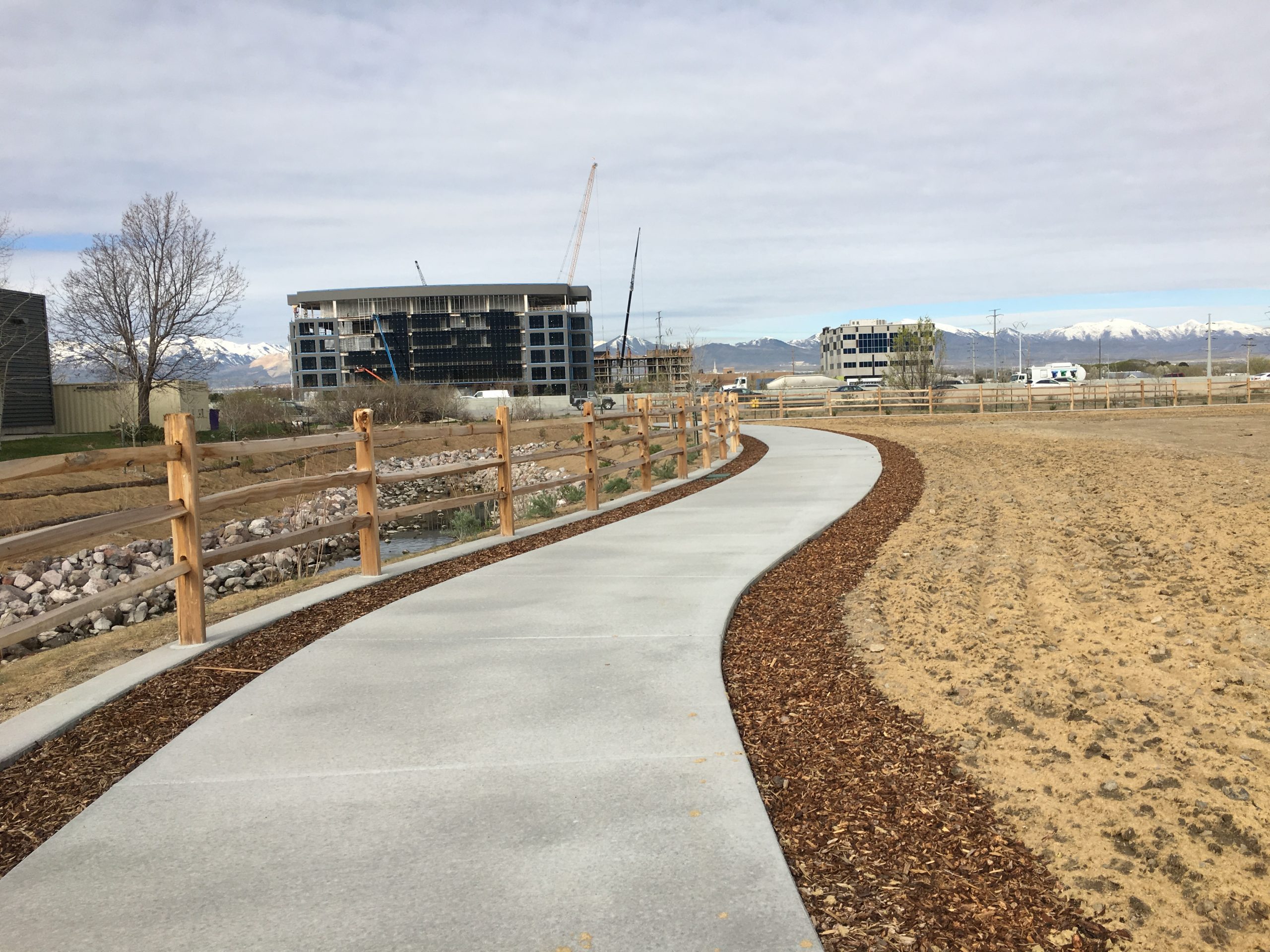 Sidewalk with wood fence following alongside the Dry Creek channel.