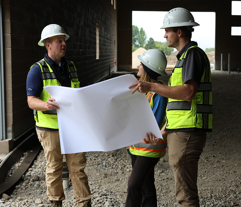 3 construction workers discussing blueprints