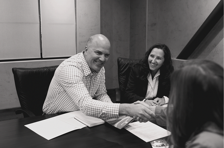 Smiling man sitting at table across from colleagues