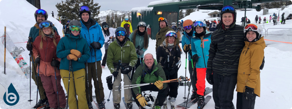 Group of smiling people in winter clothing and ski gear next to a ski lift
