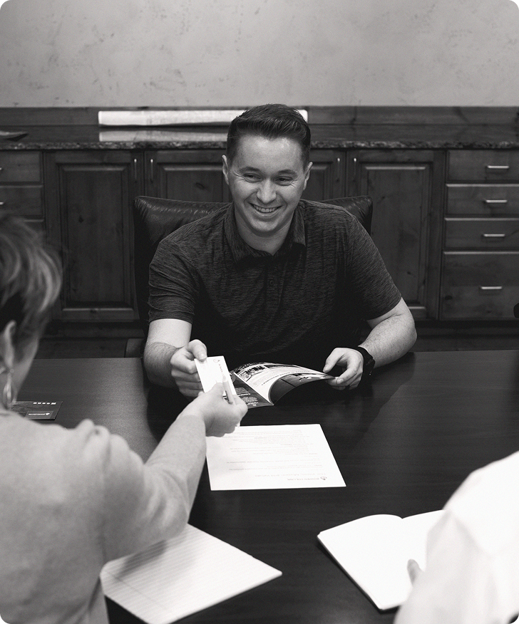 Smiling man sitting at table across from colleagues