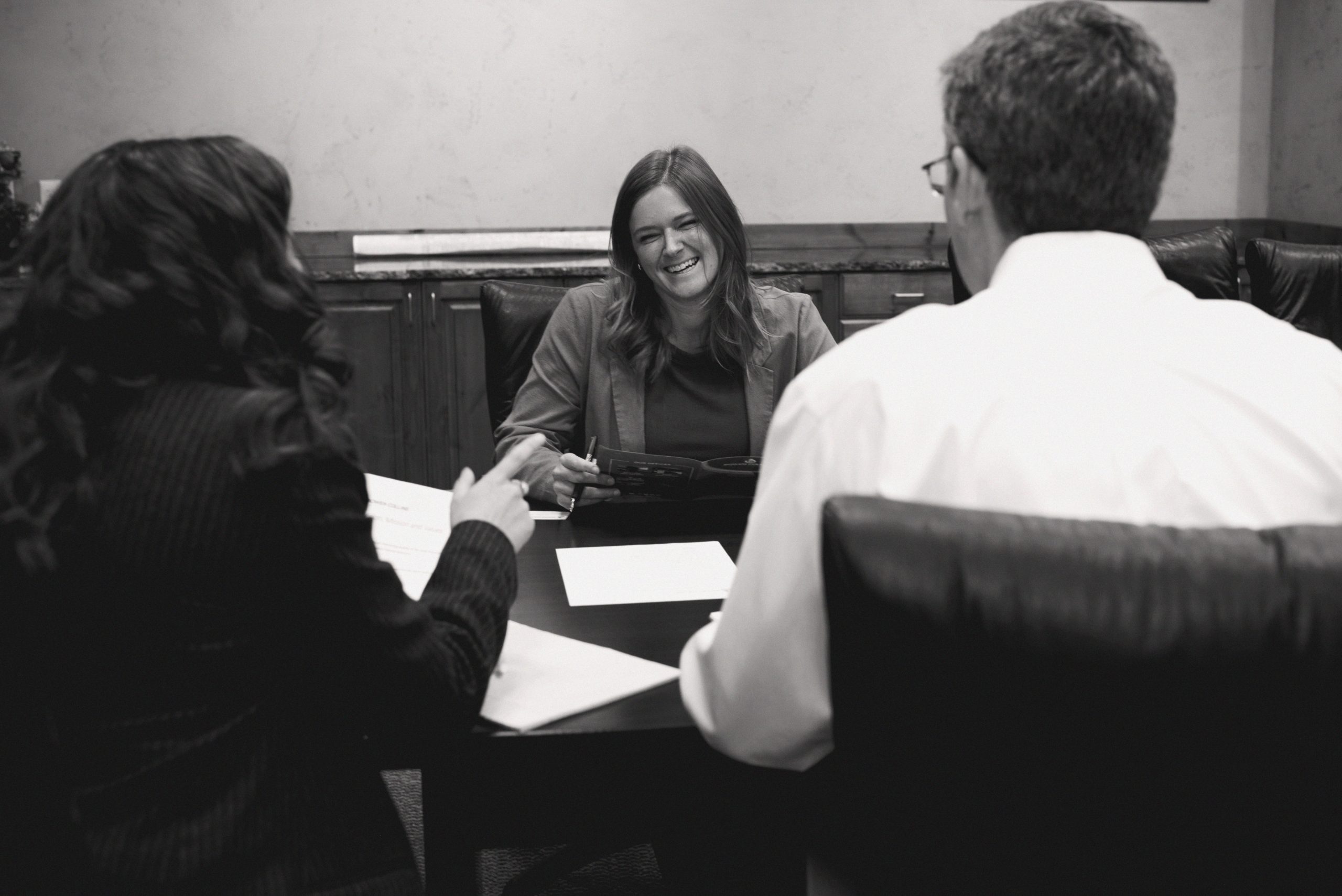 Smiling woman sitting across table from colleagues