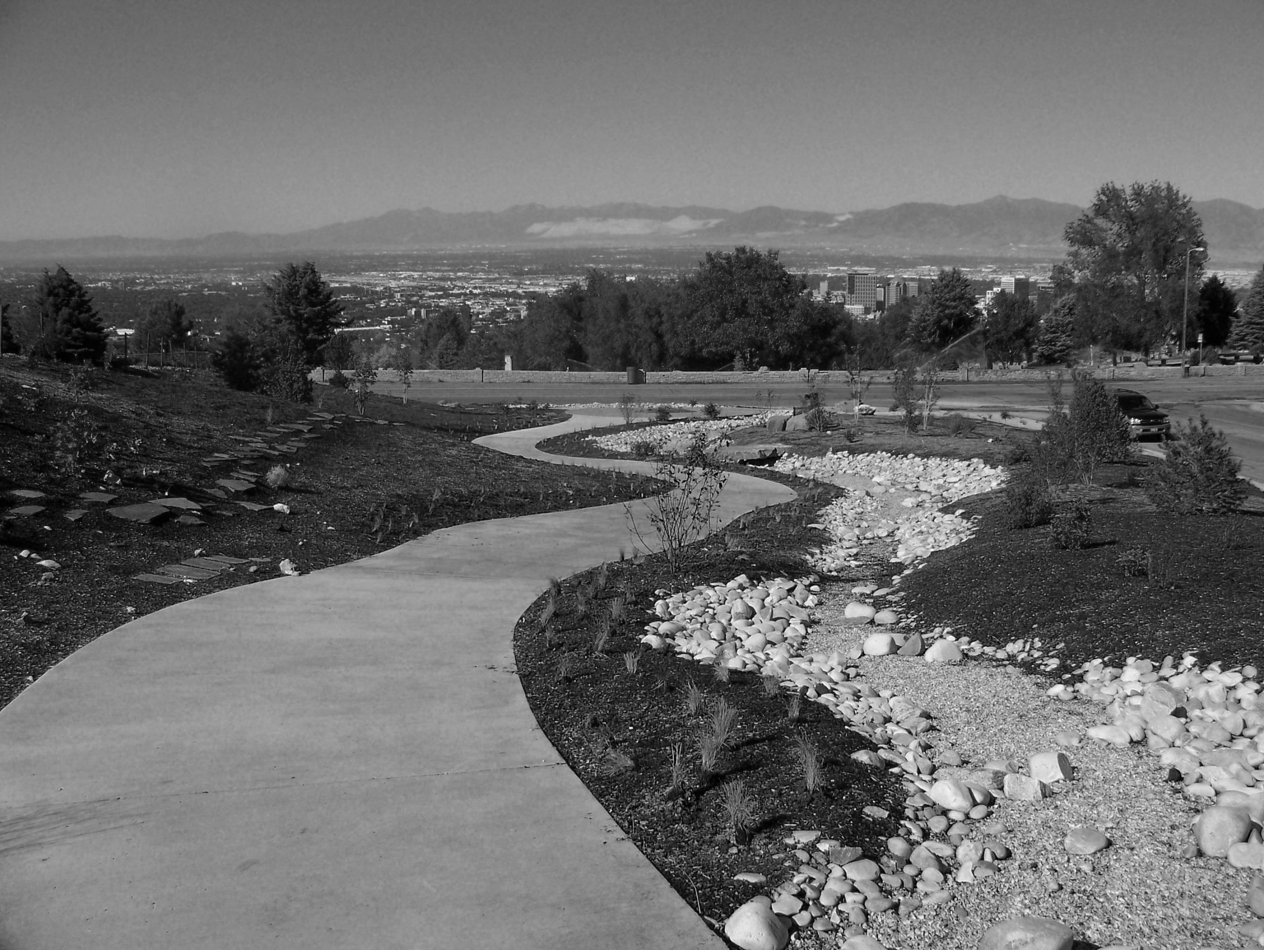 Image of paved path winding down hillside overlooking a valley